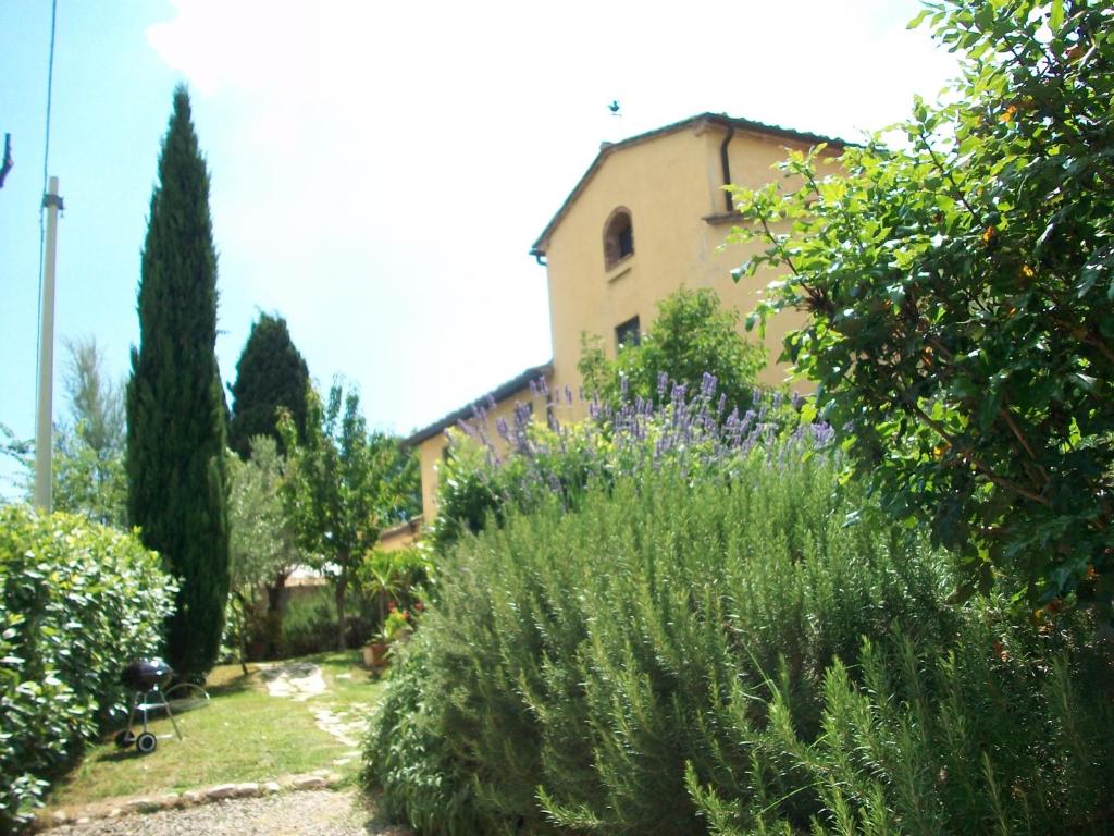 un jardín con flores púrpuras y un edificio de fondo en Casa di Campagna Maglianello en Barberino di Val dʼElsa