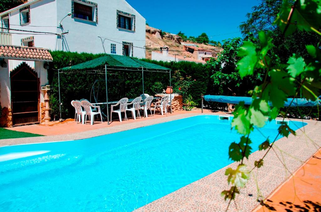 a swimming pool with chairs and a table and a house at Alojamiento Rural Pelijas in Fontanar