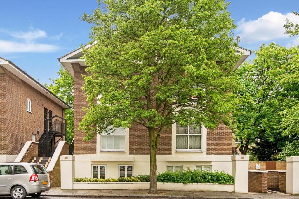 a tree in front of a brick building at Maida Vale, apartment with private terrace in London