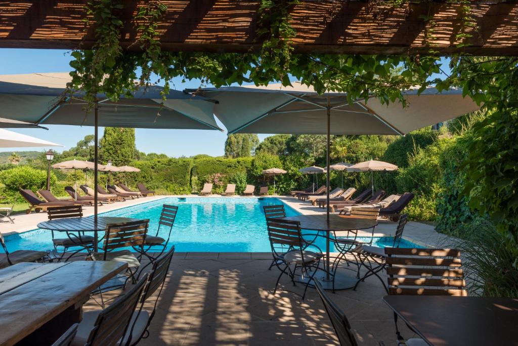a pool with tables and chairs and umbrellas at Saint-Vincent in Saint-Tropez