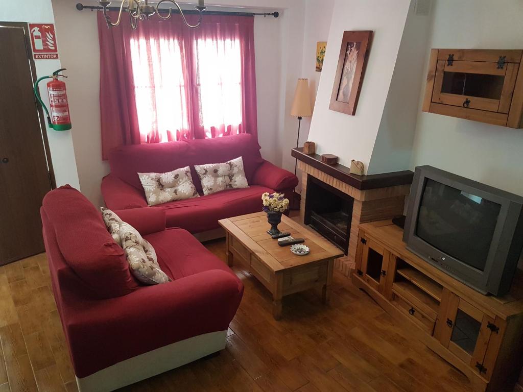 a living room with two red chairs and a television at Casita de Rosario in Cortes de la Frontera