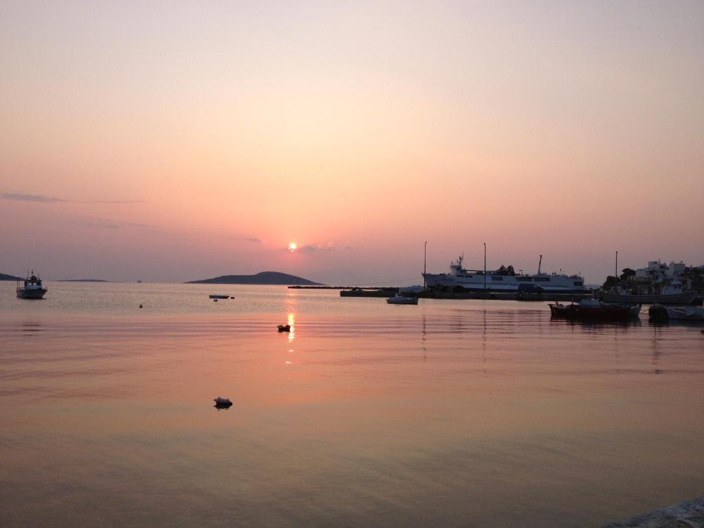 um pôr-do-sol sobre um corpo de água com barcos em Gikas Apartments em Marmari