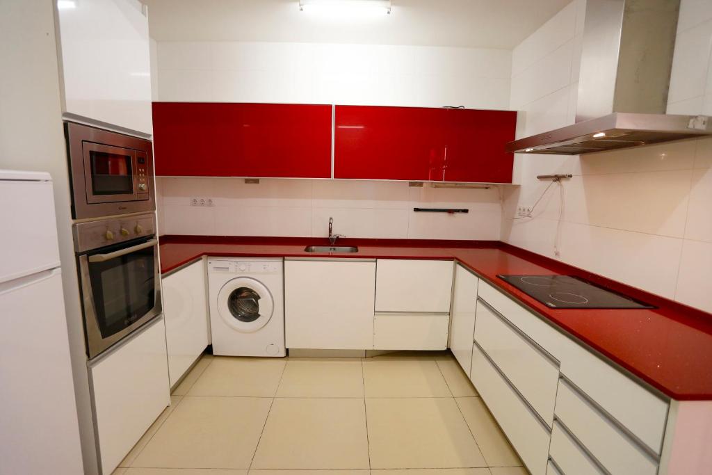 a red and white kitchen with a sink and a washing machine at Villa hortencia in Tarragona