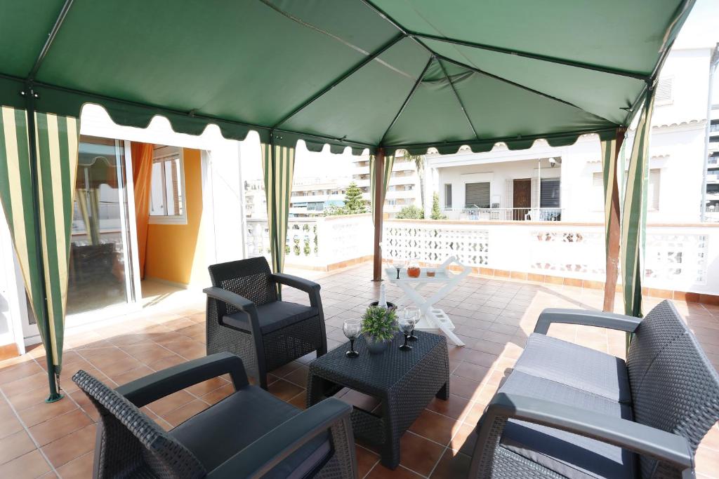 a patio with chairs and tables and a green umbrella at Villa hortencia in Tarragona