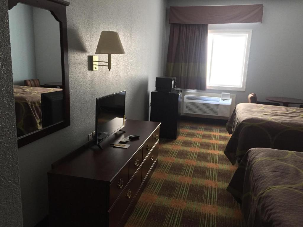 a hotel room with a desk and a bed and a mirror at Super 8 by Wyndham Sweet Springs in Sweet Springs