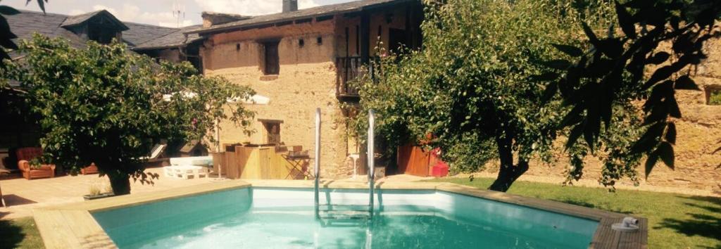 a swimming pool in front of a house with trees at Casa Rural Pico del Lugar in Villar de los Barrios