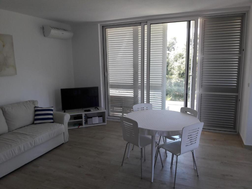 - un salon avec une table et des chaises blanches dans l'établissement Apartment Marina, à Silba