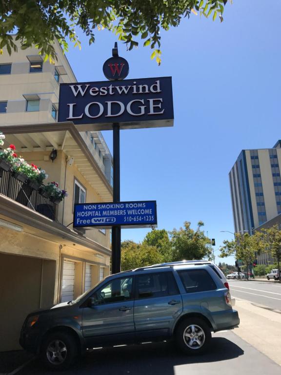 una furgoneta azul estacionada frente a un cartel de Westwind lodge en Westwind Lodge, en Oakland