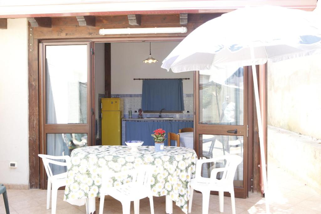 einen Tisch und Stühle mit einem Tisch und einem Sonnenschirm in der Unterkunft Ciclamino in Alcamo Marina