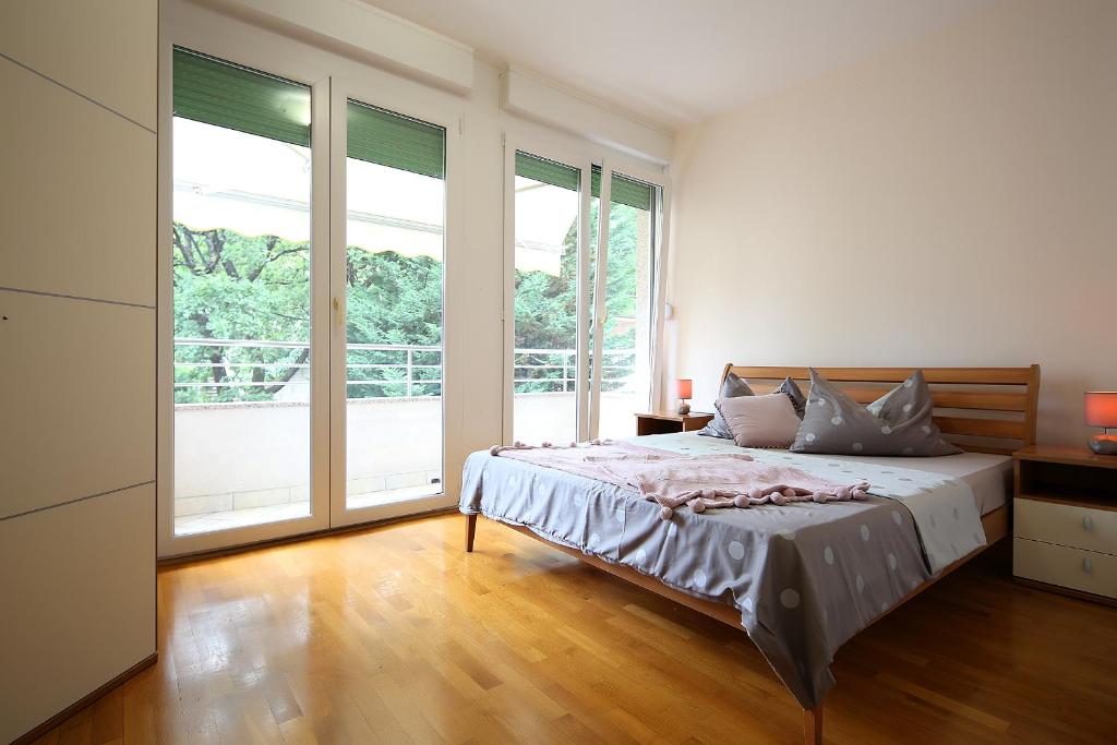 ein weißes Schlafzimmer mit einem Bett und großen Fenstern in der Unterkunft Duje in Opatija