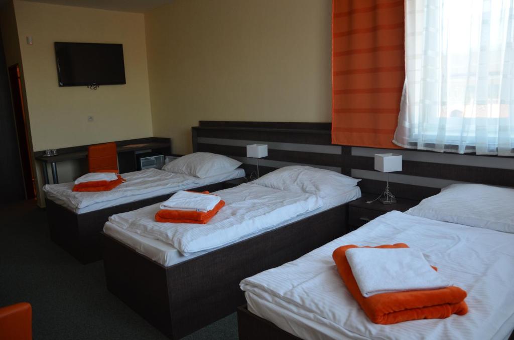 three beds in a room with orange towels on them at Penzión Rocket Club in Lučenec