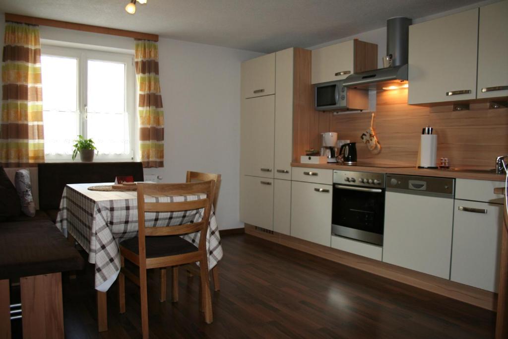 uma cozinha com armários brancos e uma mesa com uma sala de jantar em Apartments Gabl em Schönwies