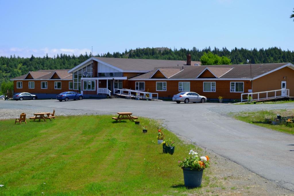 a building with a parking lot with benches and flowers at Silverwood Inn Hotel Bay Roberts in Bay Roberts