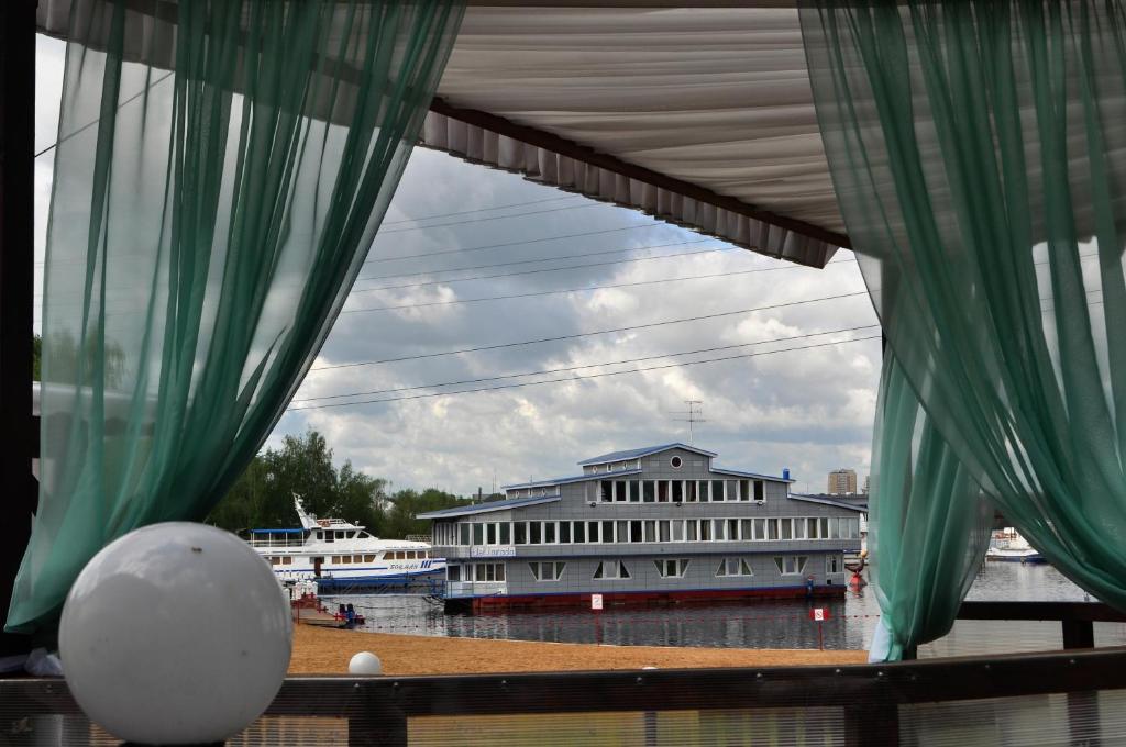 a view of a building from a window with curtains at Family hotel on the lake Lakada in Gribki