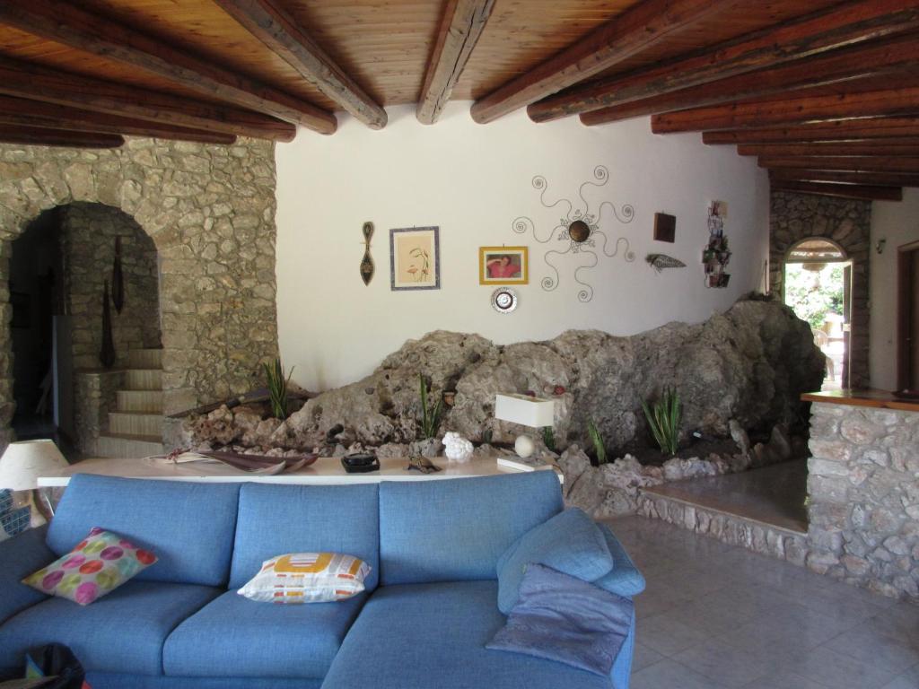 sala de estar con sofá azul y pared de piedra en Villa Federica, en Villa Targia
