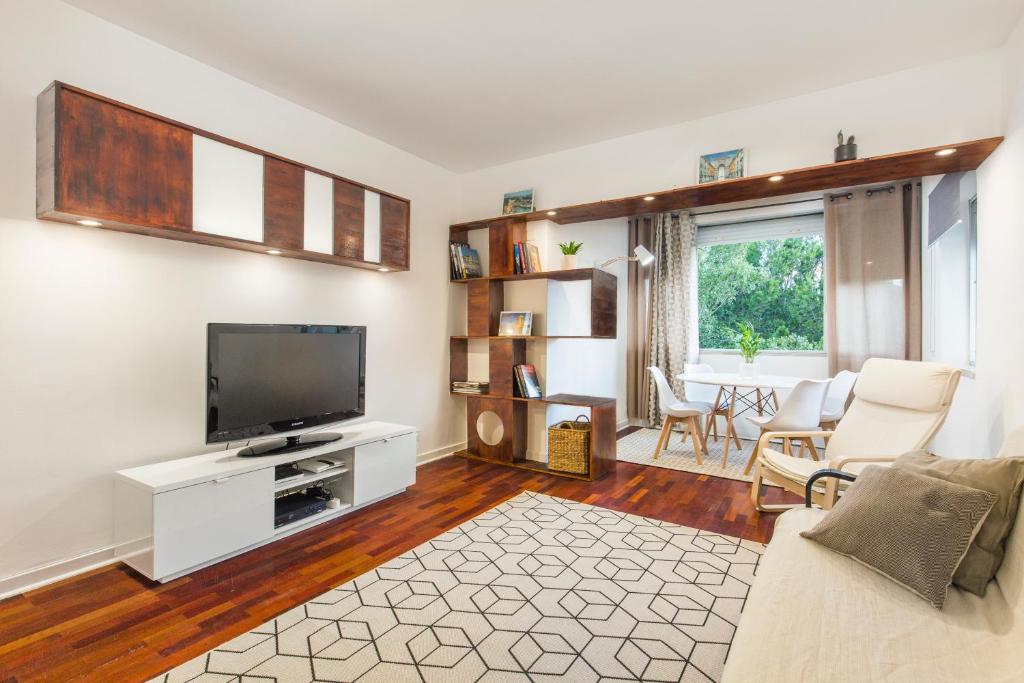 a living room with a flat screen tv and a couch at Carcavelos Beach Apartment in Cascais