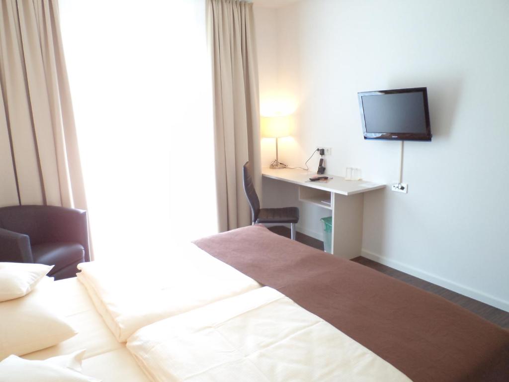 a hotel room with a bed and a desk with a television at Das Neue Hotel Am Park in Fröndenberg