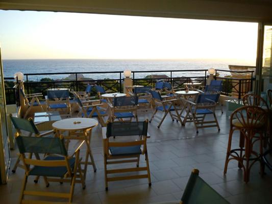 a balcony with tables and chairs and the ocean at Ammos Bay in Agios Gordios