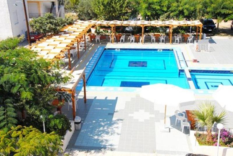 a swimming pool with tables and umbrellas next to at Hotel Aphroditi in Agia Paraskevi