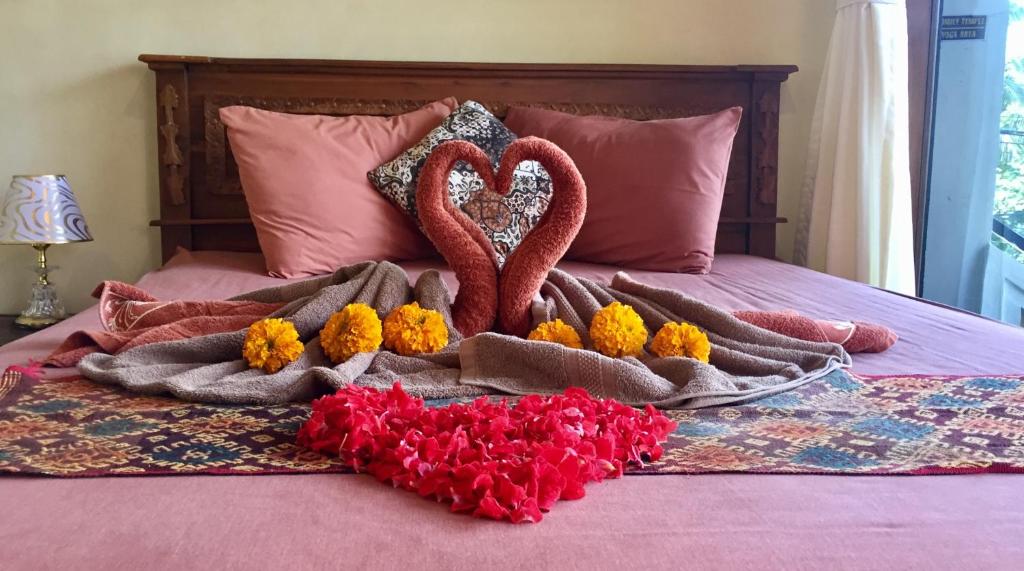 - un lit avec deux cœurs et des fleurs dans l'établissement Pondok Taman Asri Homestay, à Ubud