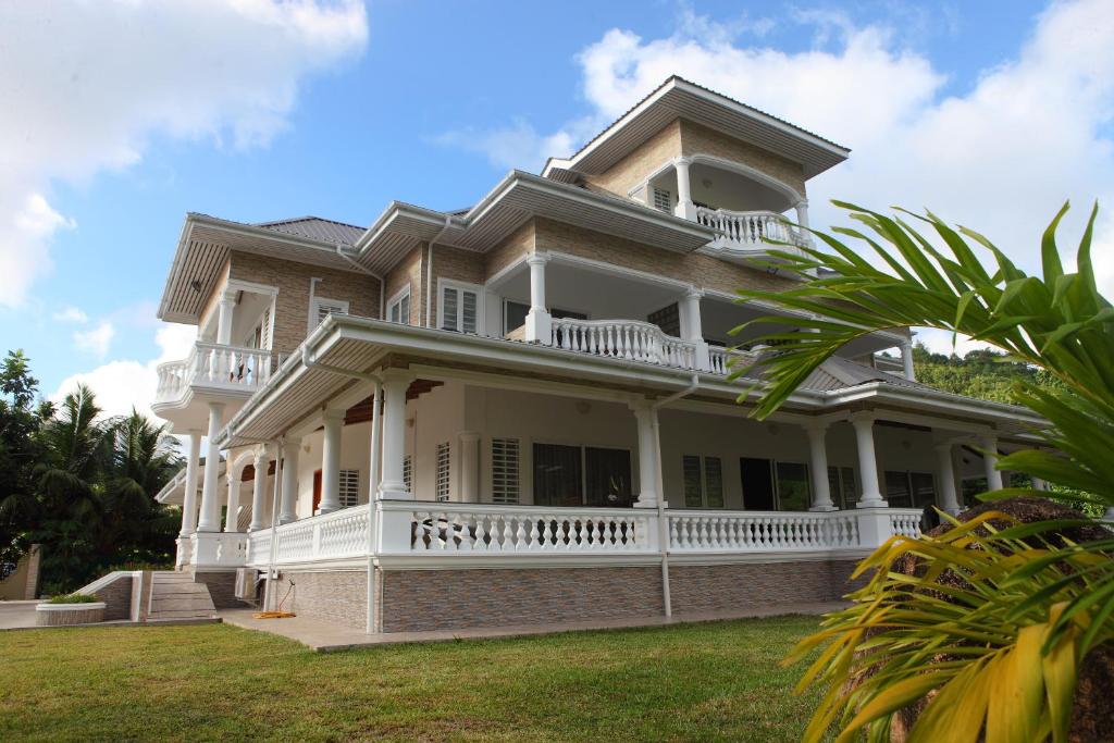una grande casa bianca con balcone su un prato di Grann Kaz Guest House a Anse a La Mouche