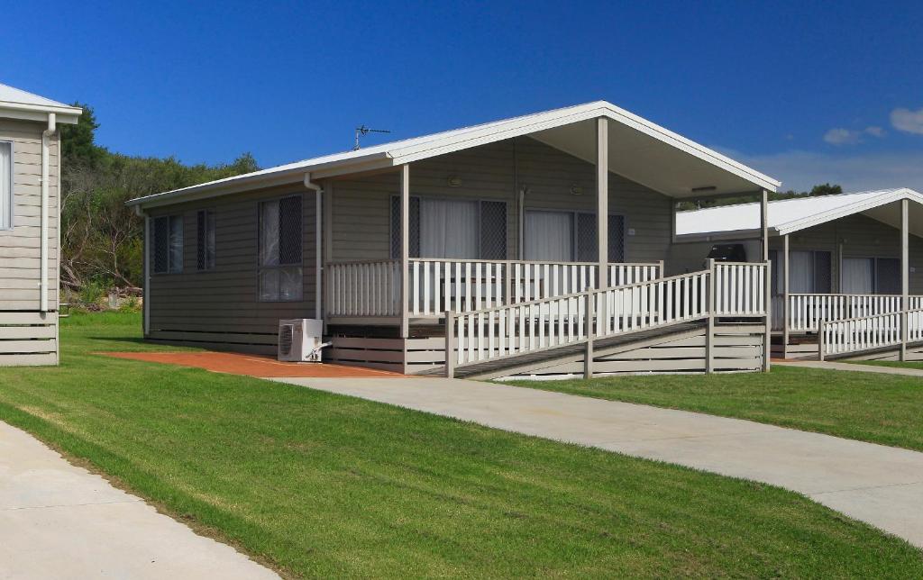 Casa marrón con porche y césped en Corrimal Beach Tourist Park, en Wollongong