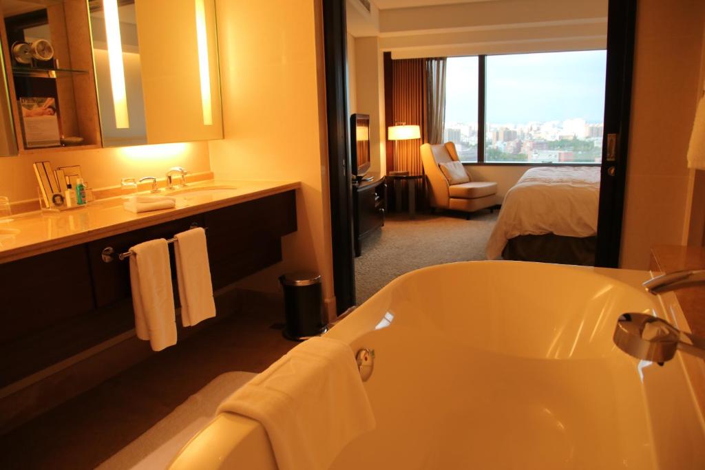 a bathroom with a tub and a bedroom with a bed at Shangri-La Far Eastern Tainan in Tainan