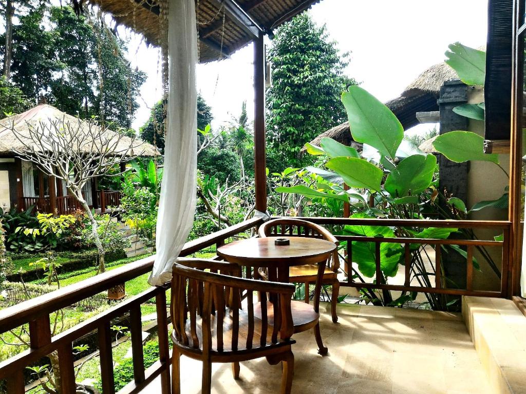 patio ze stołem i krzesłami na balkonie w obiekcie Astawa House w mieście Ubud