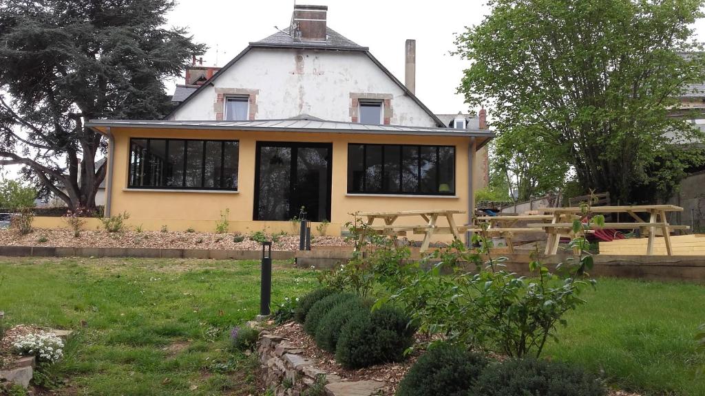 a yellow house with black windows in a yard at Tagar'étape in Étables