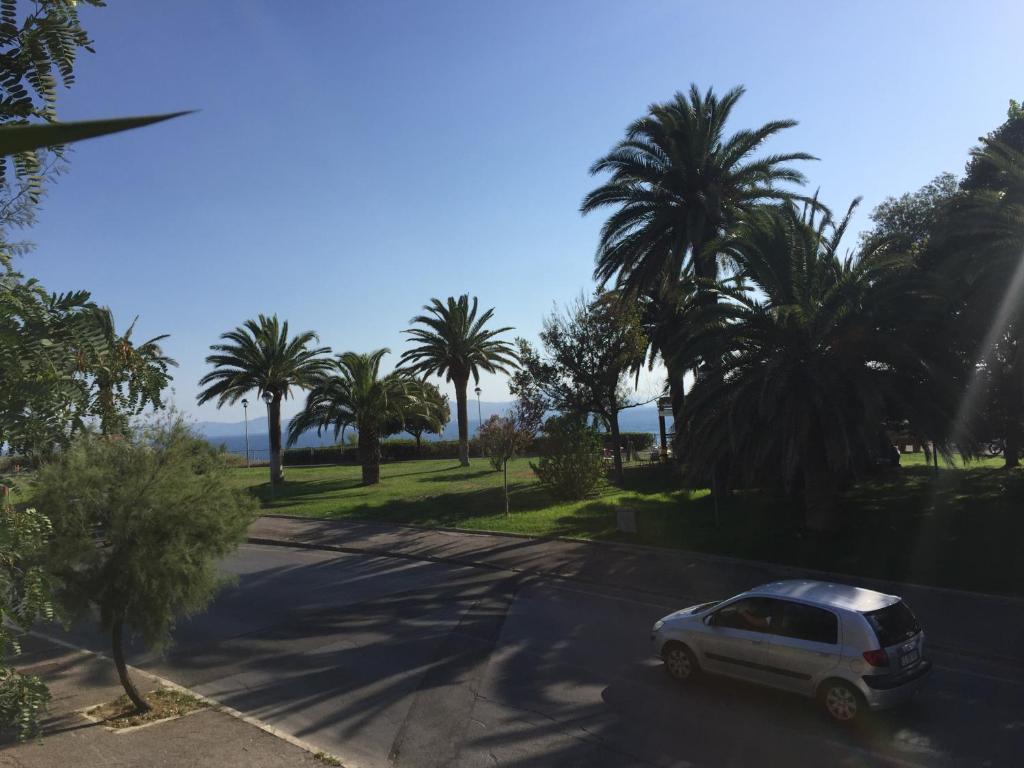 a white car parked on a street with palm trees at Apartment Salivoli in Piombino