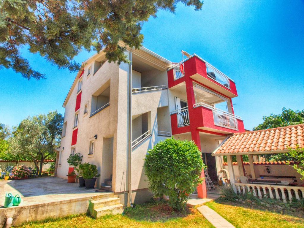 un bâtiment rouge et blanc avec un arbre dans l'établissement Apartments Božo 1418, à Peroj