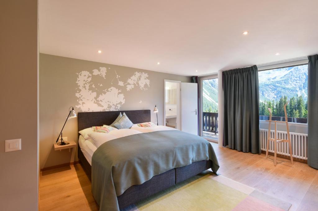 a bedroom with a large bed and a large window at Hotel Seehof-Arosa in Arosa