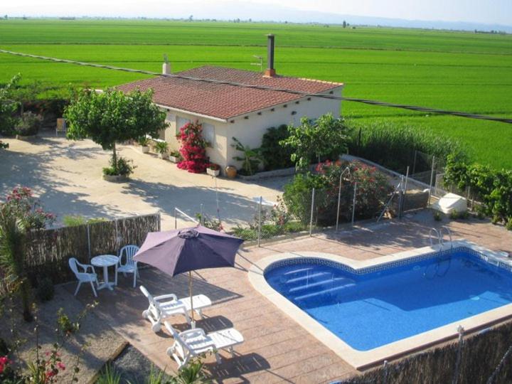 a house with a swimming pool and an umbrella at Caseta del Chato in Deltebre