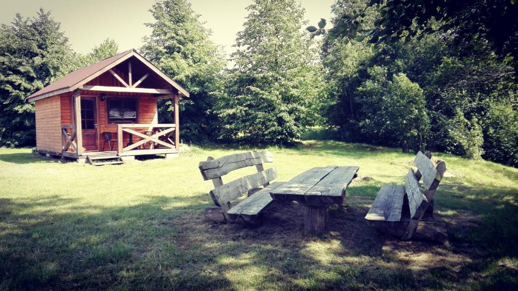 une table de pique-nique et des bancs devant un petit bâtiment dans l'établissement Mazie Upmalnieki, à Užava