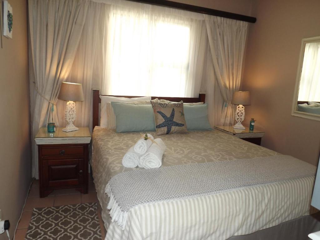 a bedroom with a bed with two lamps and a window at Stroke-One-Inn in Umkomaas