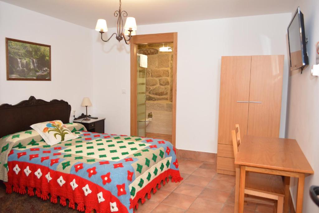 a bedroom with a bed and a wooden table at Alojamiento Pazos in Cea