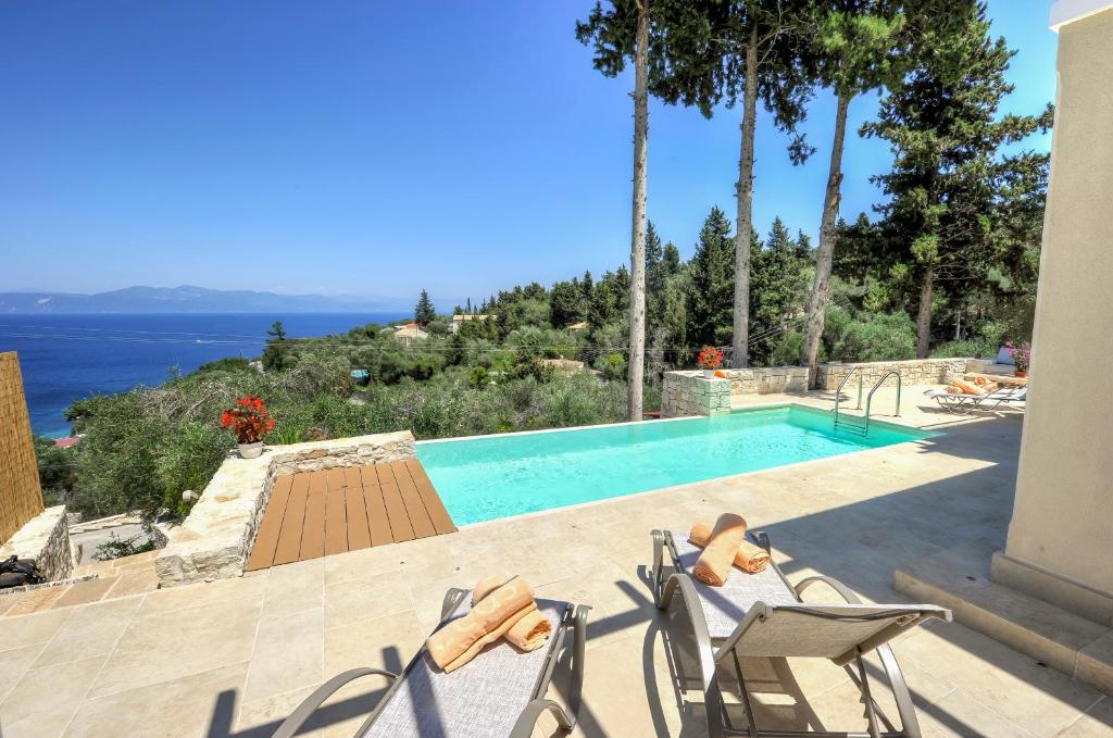 a swimming pool with chairs and a view of the ocean at Apeiron I Villa by PaxosRetreats in Oziás