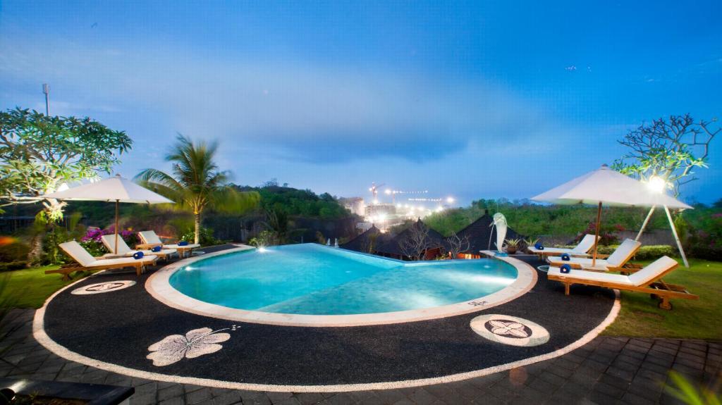 a swimming pool with lounge chairs at Puri Pandawa Resort in Uluwatu