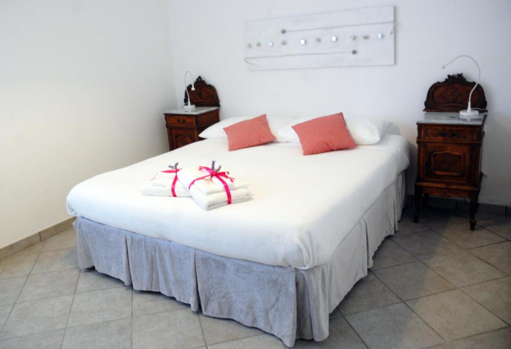 a white bed with red and white pillows on it at B&B La Montagna Rosa in Castelnuovo