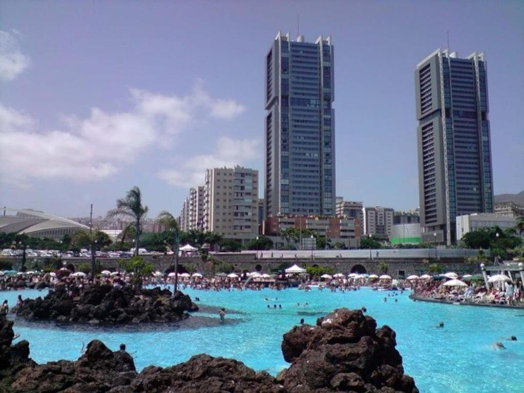 a large swimming pool with people in the water with buildings at Apartamento Torre Uno Santa Cruz in Santa Cruz de Tenerife