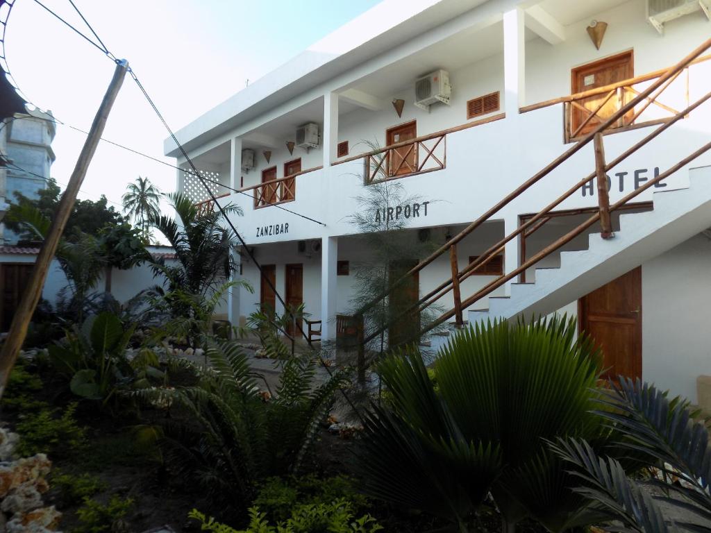 un bâtiment avec des escaliers et des plantes devant lui dans l'établissement 27 Cafe Zanzibar Airport Hotel, à Zanzibar City