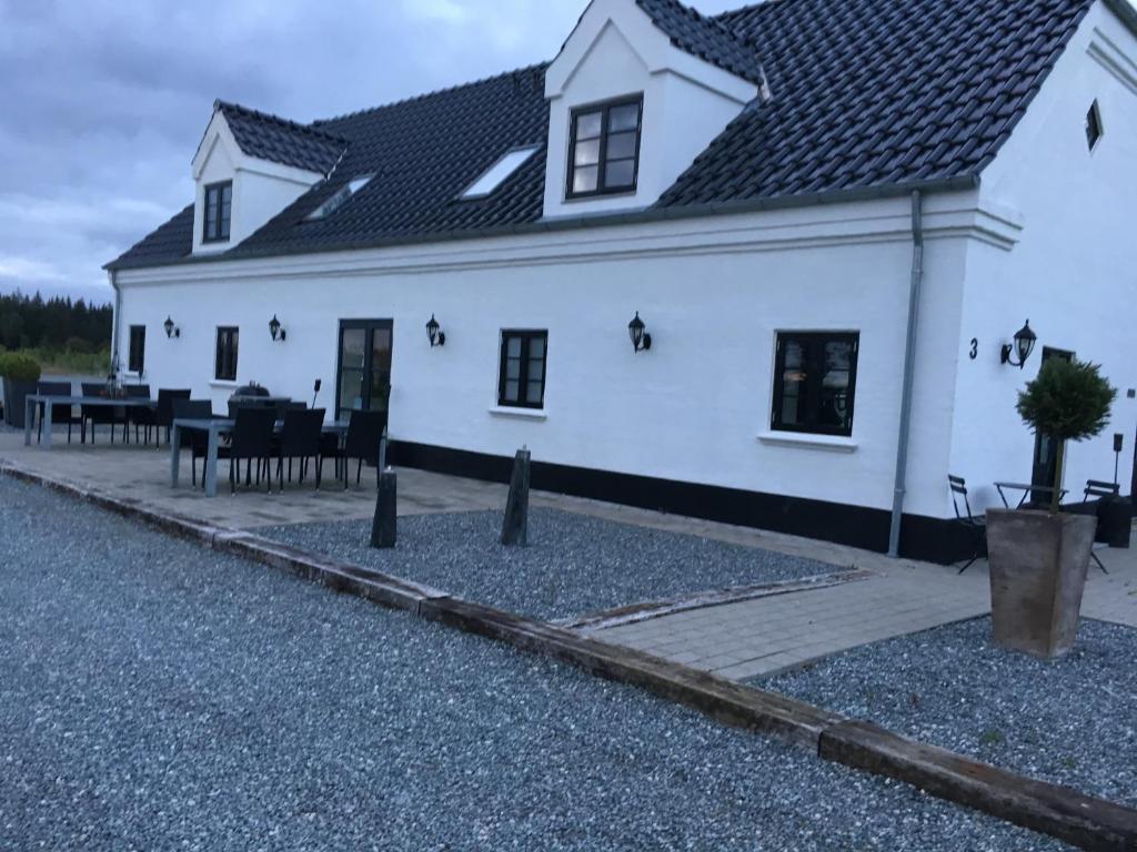 a white house with tables and chairs in front of it at Hedegaarden in Engesvang