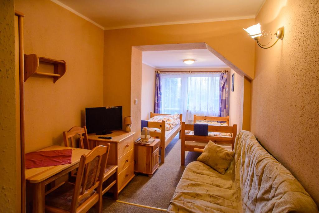 a living room with a couch and a table and a television at Chata Baryła in Sulęczyno