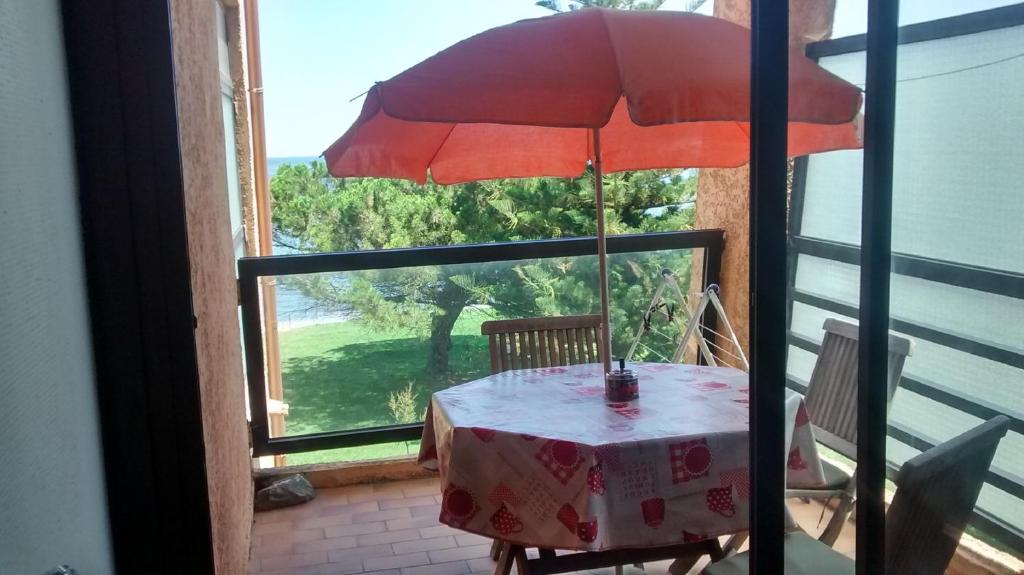 サンタ・ルシア・ディ・モリアニにあるStudio les pieds dans l'eauのバルコニーにテーブルと赤い傘