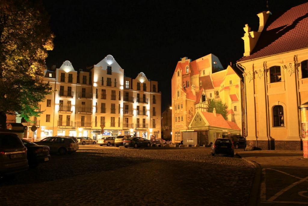 a city street at night with buildings and cars at Śródka Boutique Hotel in Poznań