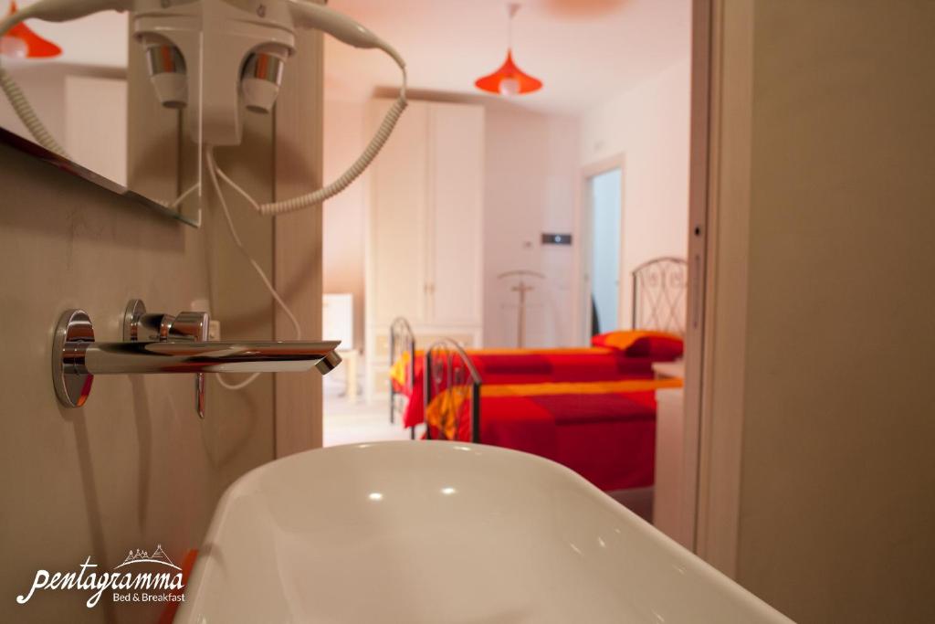アルベロベッロにあるB&B Pentagrammaのバスルーム(白い洗面台、赤いベッド付)
