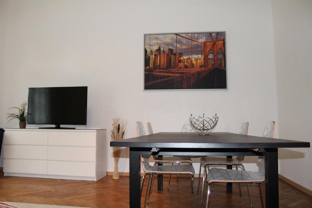 a dining room with a table with chairs and a tv at Murtal Apartments in Knittelfeld