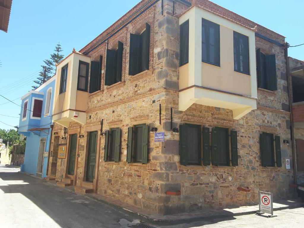 un vecchio edificio in mattoni con finestre con persiane verdi di Frourio Apartments a Chio (Chios)