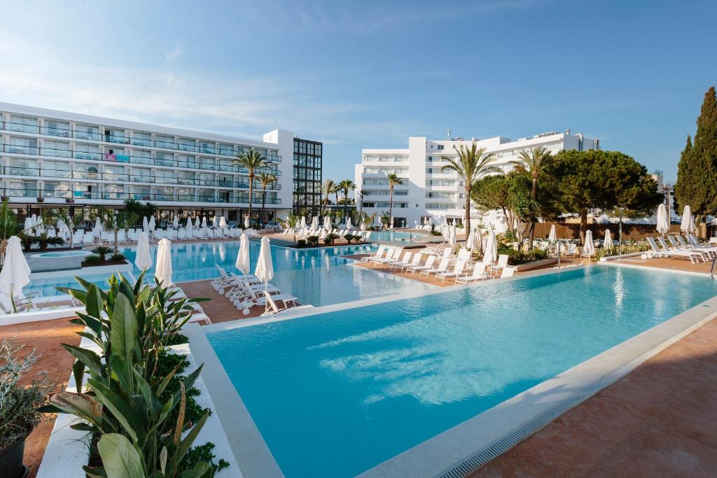a large swimming pool with lounge chairs and a hotel at AluaSoul Ibiza - Adults only in Es Cana
