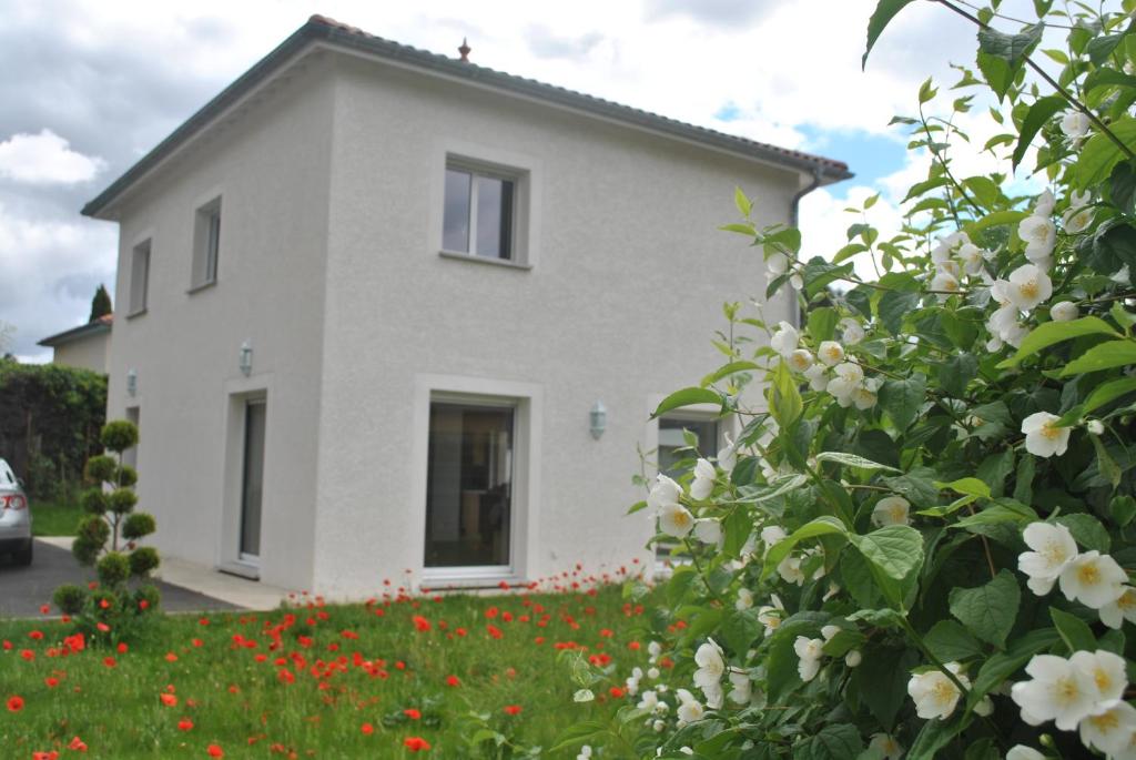 uma casa branca com flores à frente em La Marina em Chassieu